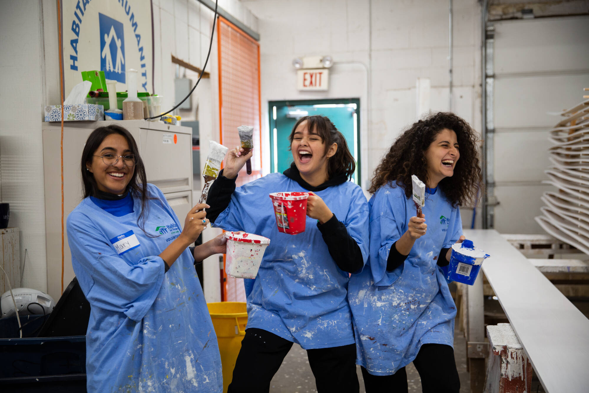 A group of students pose for a photo with paintbrushes during a volunteer event as part of Make a Difference Day. Taken October 27, 2018.